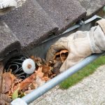 man taking leaves out of gutter