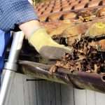 man taking leaves out of gutter