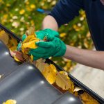 man taking leaves out of gutter