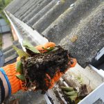 A gutter cleaner cleaning a dirty gutter