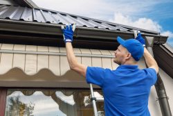 Man installing house roof gutter system