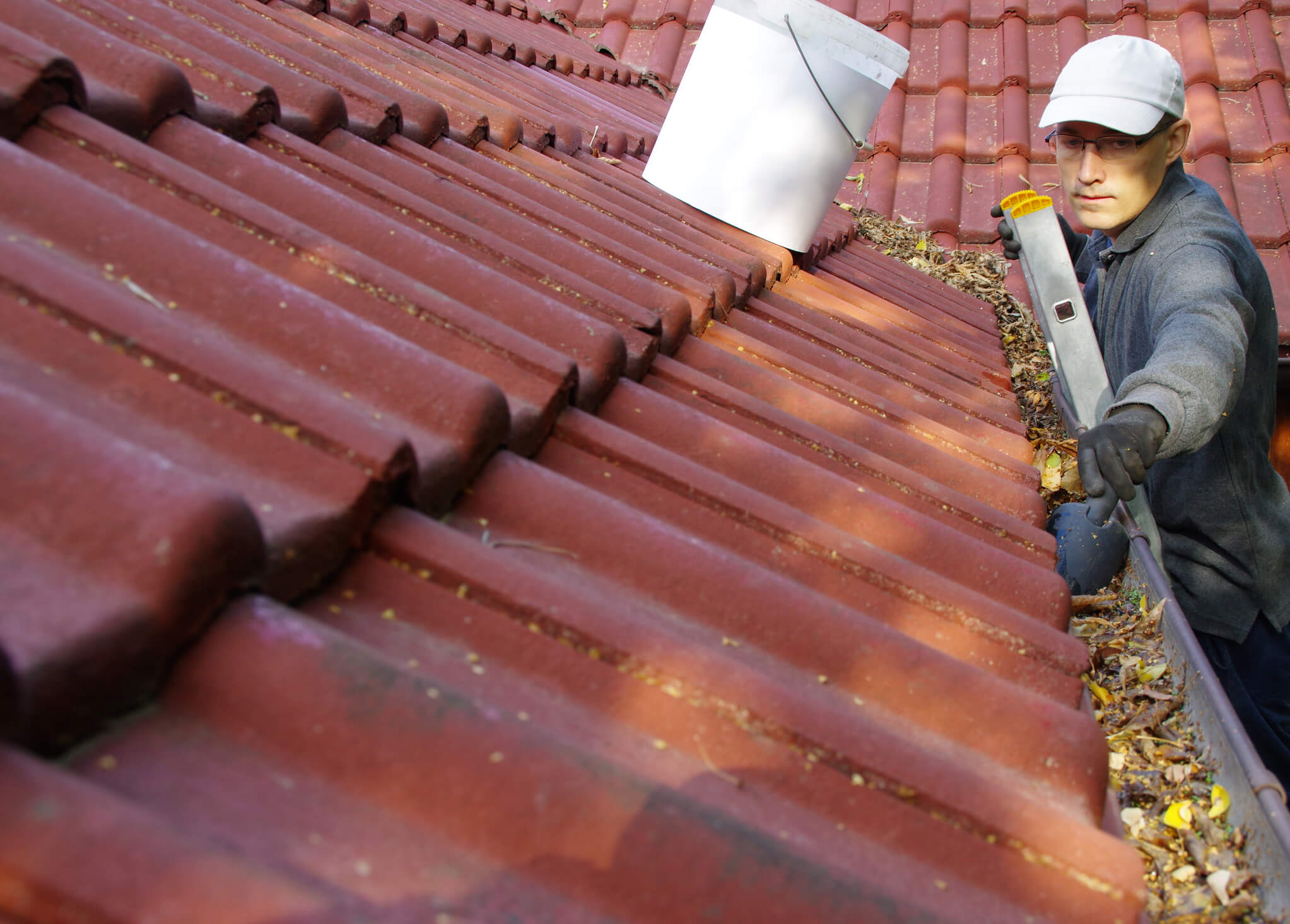 Man cleans the gutter on a roof.